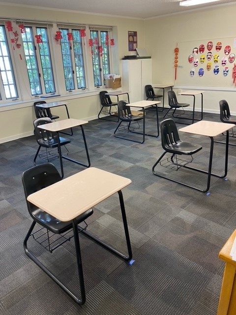 Physically distanced desks with tape markings on the floor. 