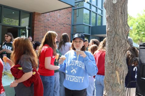 Senior Amelia H. drinks a glass sparkling cider at Chalk Day while sporting her college sweatshirt.