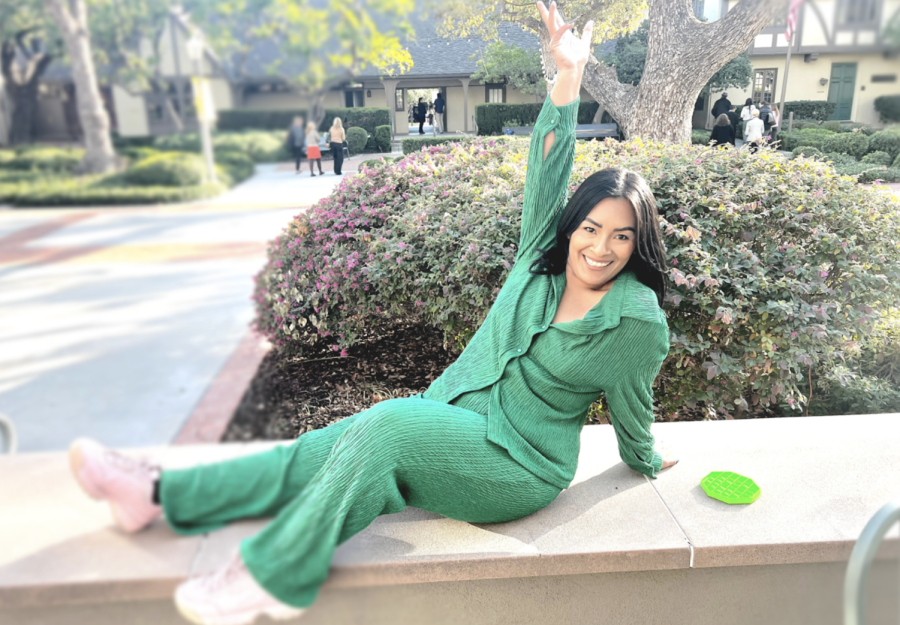 Ms. Emma Hoo, Westridges Lower and Middle School Assistant, poses in front of Madeline Court in a vibrant green jumper.