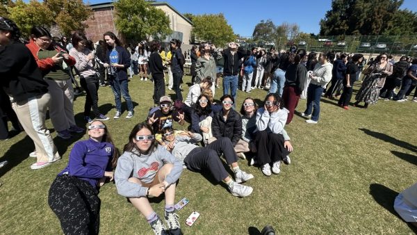 A group of Upper School students sit on the floor, excited to watch the eclipse. 