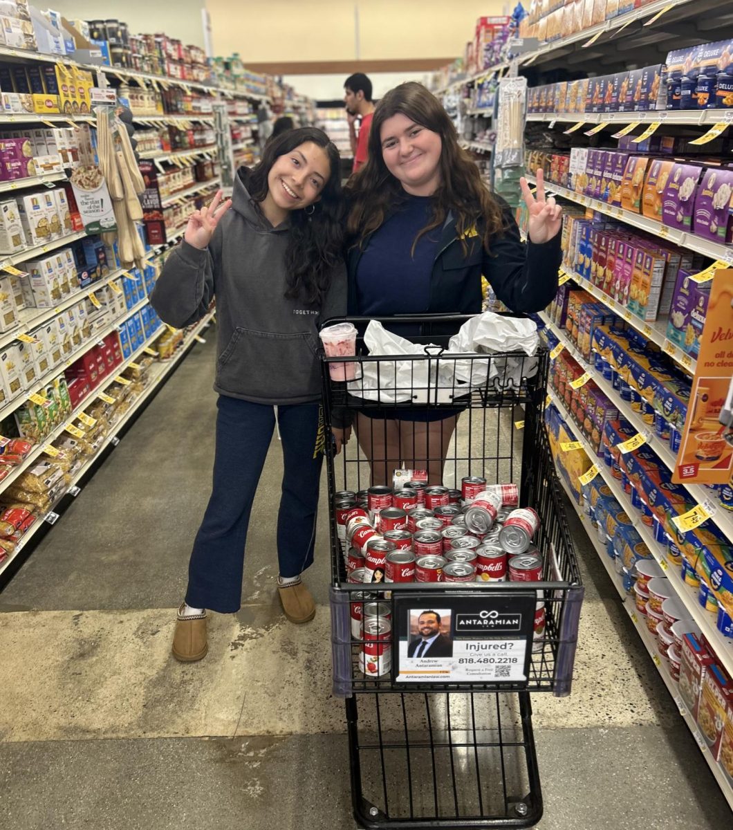 Spyglass staff writer Lilah R. '25 and I pose with our cart full of soup cans. We bought around 100 cans during this trip to the store. 