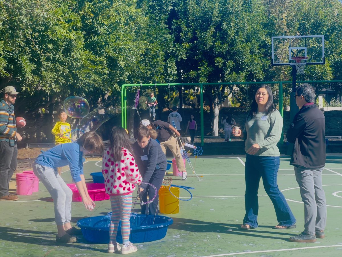Parents and children enjoy the bubble station and playground swings.