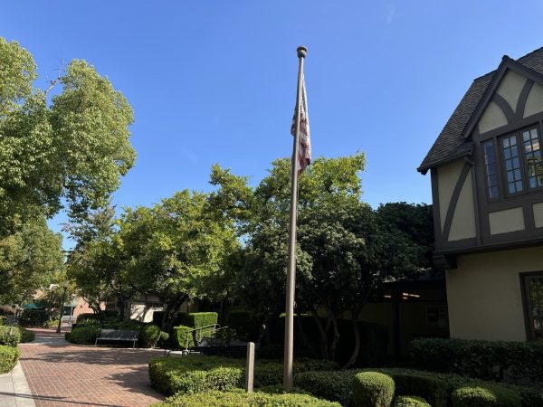 An old, sun-bleached American flag hangs in front of the Main Hall building.  