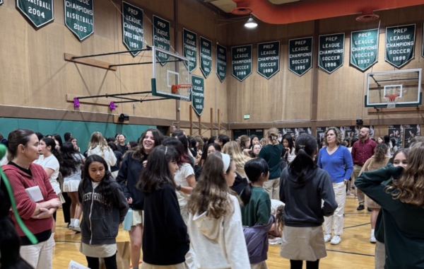 Students gather in the gym at the start of a Tigers, Stripes, and Cubs meeting searching for their group.